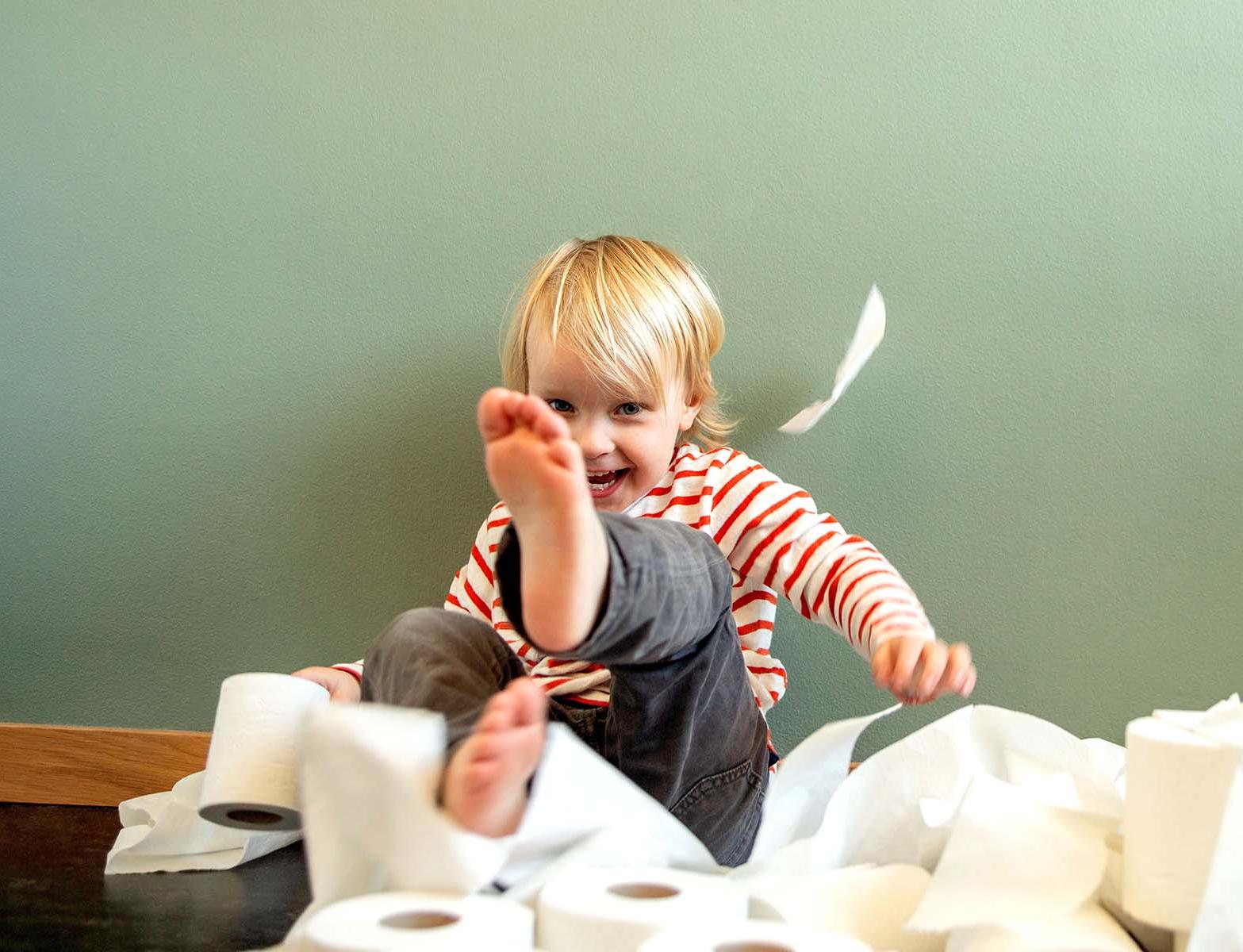 一个蹒跚学步的孩子高兴地乱扔卫生纸.